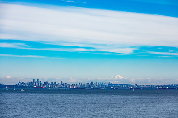 Vancouver City at the Western Canadian Pacific Ocean coast with oil tankers anchored in harbor and Mount Baker in the far distance shadowing the cityscape skyline, Biritish Columbia, BC, Canada