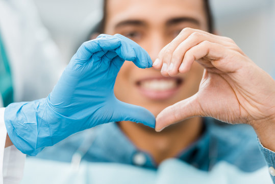 selective focus of heart shape hands of dentist and african american patient