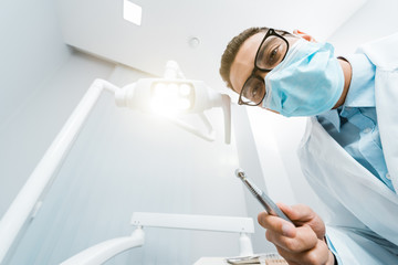 african american dentist in white coat and mask with drill in hand
