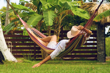 Beautiful woman relaxing in hammock in tropical garden.