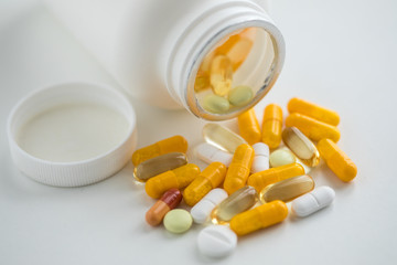 Pillendose mit gelben und weißen Pillen Kapseln und Tabletten auf weißen Hintergrund