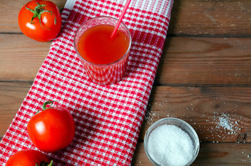 Tomato juice in glass with fresh tomatoes and salt. Rustic wooden background. Selective focus.