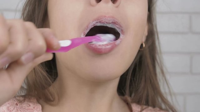 The child is brushing teeth. Teenager girl brushes her teeth. Child brushing teeth close up.