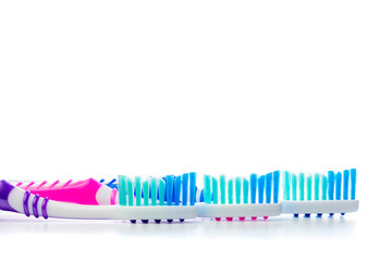 three multi-colored toothbrushes on isolated white background