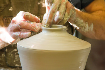 Artist potter in the workshop sculpting ceramic vase. Hands closeup. Small artistic craftsmen business concept. 