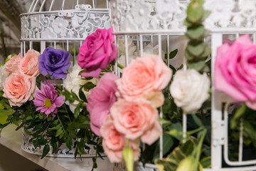 Various bridal flower heads in vintage ornate bird cage as bloom decoration at a wedding reception