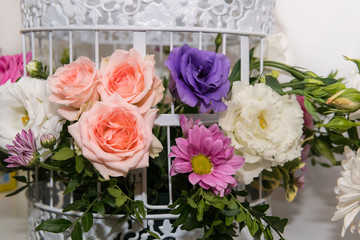 Various bridal flower heads in vintage ornate bird cage as bloom decoration at a wedding reception