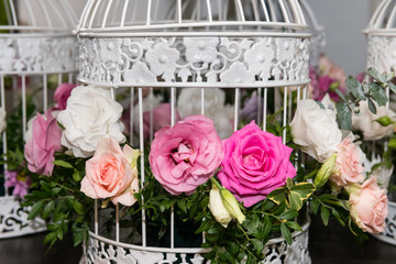 Various bridal flower heads in vintage ornate bird cage as bloom decoration at a wedding reception