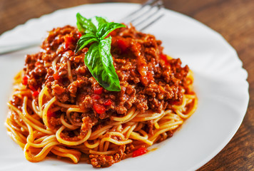 Traditional pasta spaghetti bolognese in white plate on wooden table background