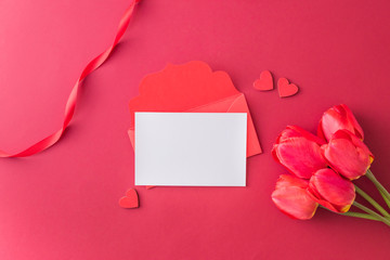 Mockup white greeting card, red  hearts and envelope with red tulips on a red background