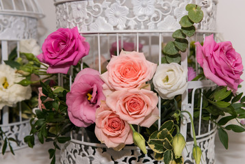 Various bridal flower heads in vintage ornate bird cage as bloom decoration at a wedding reception