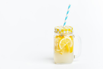 A jar of homemade lemonade and lemons on a white background.