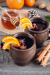 Hot mulled wine with orange, cinnamon, honey and anise on wooden background.