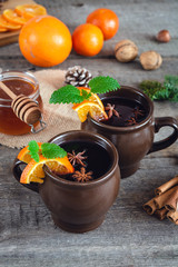 Hot mulled wine with orange, cinnamon, honey and anise on wooden background.