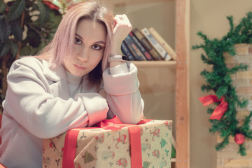 Cute cute girl in clothes santaclaus holding a gift with a green ribbon lying on the bed against the Christmas tree. teenager girl hold presents gift box on Christmas tree background