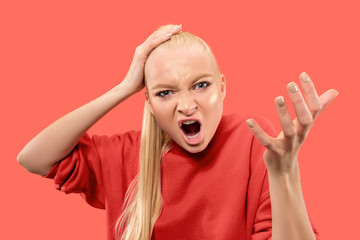 Angry woman looking at camera. Aggressive business woman standing isolated on trendy coral studio background. Female half-length portrait. Human emotions, facial expression concept