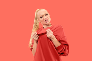 Angry woman looking at camera. Aggressive business woman standing isolated on trendy coral studio background. Female half-length portrait. Human emotions, facial expression concept