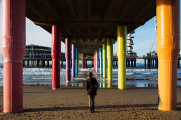 girl walking on the beach with colorful pillars of the pier by the sea - 240996838