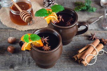 Hot mulled wine with orange, cinnamon, honey and anise on wooden background.