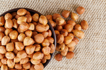 Peeled hazelnuts in a wooden, dark brown cup on a burlap cloth. Super Food, Raw.