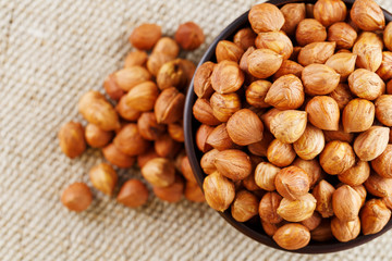 Peeled hazelnuts in a wooden, dark brown cup on a burlap cloth. Super Food, Raw.