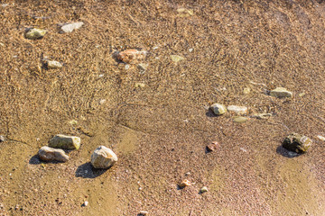aerial local object scene of wet small stones and sand background texture beach from above near sea waves wallpaper pattern with empty copy space for your text   