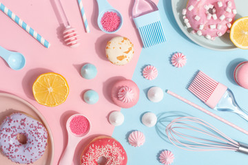 Kitchen utensils and tools, pastries and sweets on a pink and blue background. Top view. Copy space.