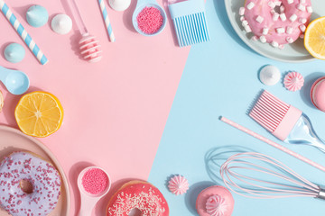 Kitchen utensils and tools, pastries and sweets on a pink and blue background. Top view. Copy space.