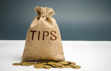 Money bag with the word Tips. Award for good service in the cafe / restaurant. A gratuity is a sum...