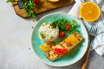 Grilled Salmon with Grapefruit and Orange Sauce and rice garnish on a light stone or concrete table.
