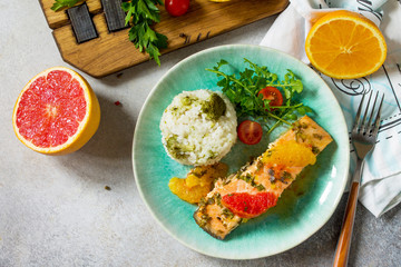 Grilled Salmon with Grapefruit and Orange Sauce and rice garnish on a light stone or concrete table. Top view flat lay background.