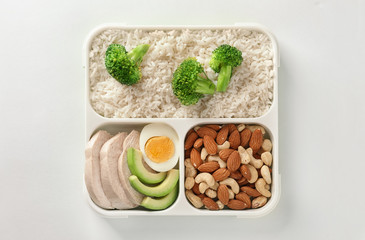 Fototapeta na wymiar Container with natural healthy lunch on white background, top view. High protein food