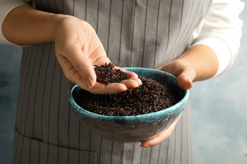 Woman with bowl of uncooked black rice, closeup