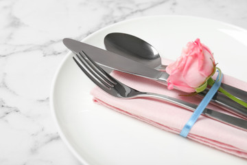 Beautiful table setting with cutlery, napkin and plate on marble background, closeup