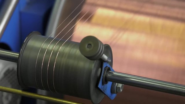 Industrial cable production. Part of production equipment. Copper wire is strung like a string. Productions of flexible multicore cable. The wire is twisted into conductive wires and uninsulated wires