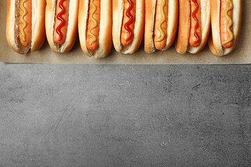 Tasty fresh hot dogs on grey background, top view. Space for text