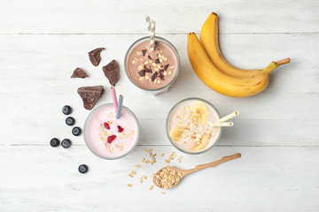Flat lay composition with protein shakes and ingredients on wooden table