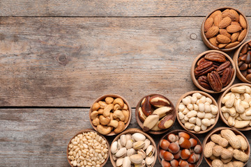 Flat lay composition with organic nuts and space for text on wooden background, top view. Snack mix