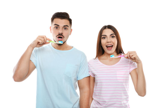 Happy couple brushing teeth on white background