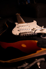 Close-up of a sunburst-colored electric guitar covered with black paint removed at certain points...