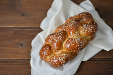 Traditional Jewish sweet Challah bread on a wood plate on wooden table / background with copy space