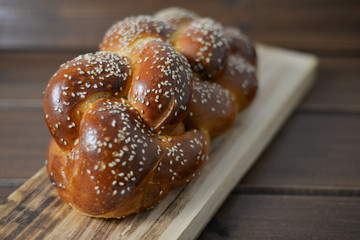 Traditional Jewish sweet Challah bread on a wood plate on wooden table / background with copy space