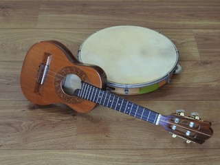 Close-up of two Brazilian musical instruments: cavaquinho and pandeiro (tambourine) on a wooden surface. They are widely used to accompany samba and choro, two popular  Brazilian rhythms.