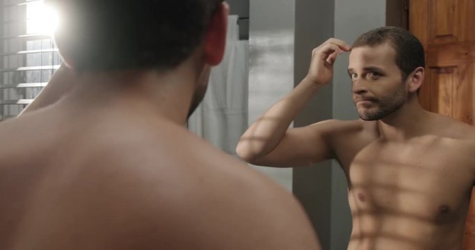 Young Man In Bathroom Worried About Premature Receding Hairline