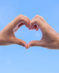 Hands put together in heart shape blue sky background. Love symbol concept. Hand heart gesture forms shape using fingers. Male hands in heart shape gesture symbol of love and romance