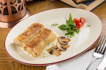 Crepes stuffed with sour cream and mushroom for breakfast on wooden table