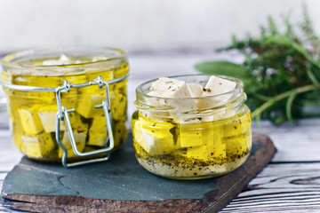 Marinated feta in a glass bath on a wooden background