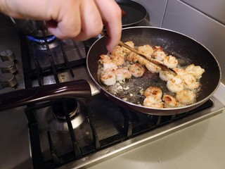 Cooking shrimps with butter in a black pan