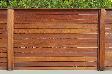 The fence around the house of wooden planks and wooden pillars, based on a concrete base