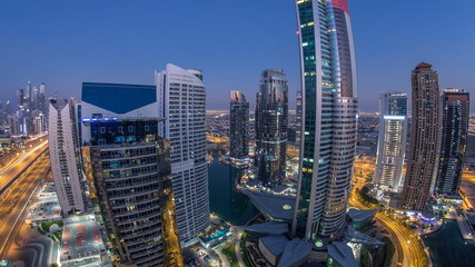 Obraz premium Buildings of Jumeirah Lakes Towers after sunset with traffic on the road day to night timelapse.
